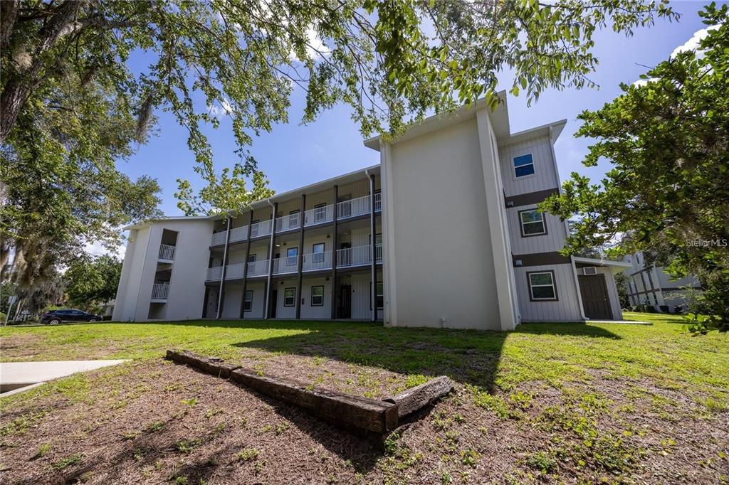 A three-story apartment building exterior with white siding and a covered walkway — 6519 W NEWBERRY ROAD UNIT 412, GAINESVILLE, FL