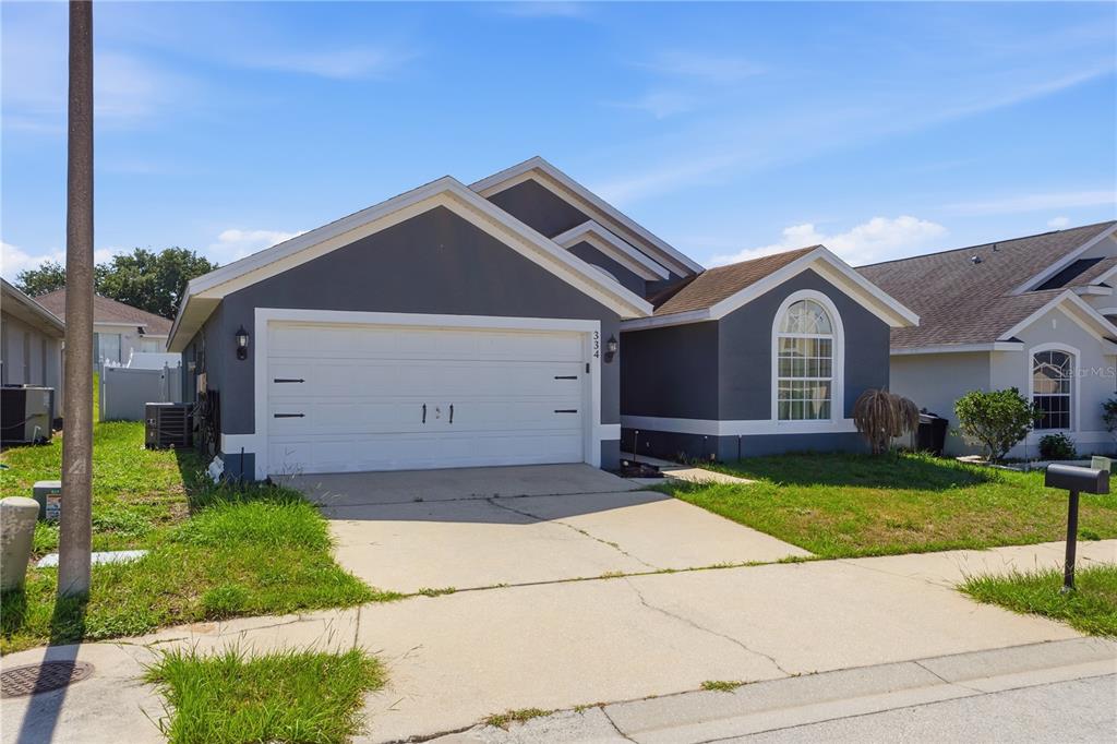 A single-story house with a gray exterior, a two-car garage, and a concrete driveway — 334 BRAYTON LANE, DAVENPORT, FL