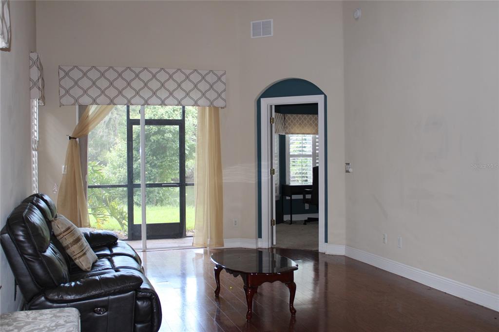 A living room with hardwood floors, a leather sofa, and a doorway to an office — 4961 ANNISTON CIRCLE, TAMPA, FL