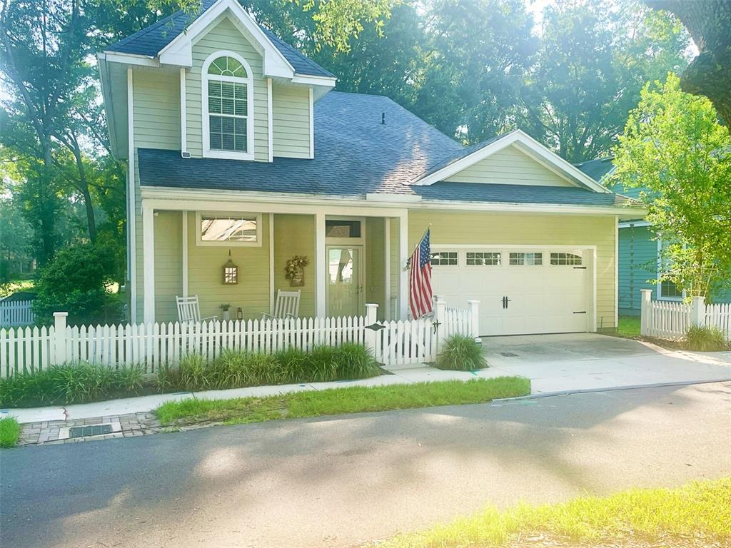 A two-story house with light green siding, a white picket fence, and a garage — 10334 SW 51ST LANE, GAINESVILLE, FL