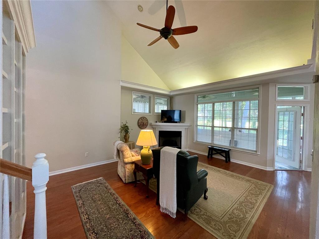 A living room with hardwood floors, a fireplace, vaulted ceilings, and a ceiling fan — 10334 SW 51ST LANE, GAINESVILLE, FL