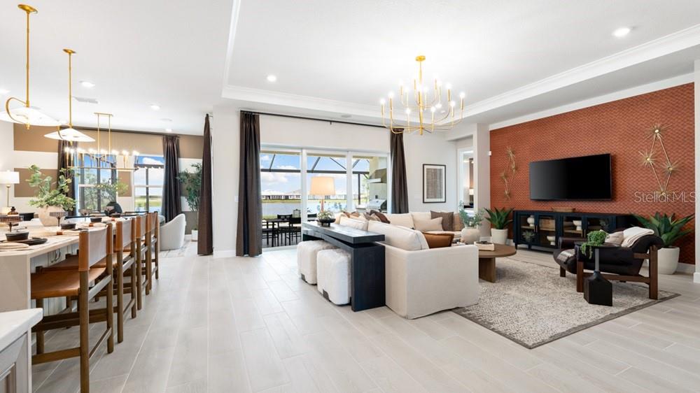 An open-concept living room and kitchen featuring a textured orange accent wall and tile flooring — 13481 MANAROLA WAY, ENGLEWOOD, FL