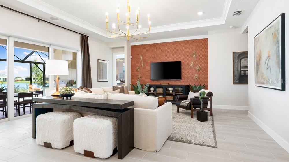 A living room features a textured orange accent wall, a television, and a neutral sofa — 13481 MANAROLA WAY, ENGLEWOOD, FL