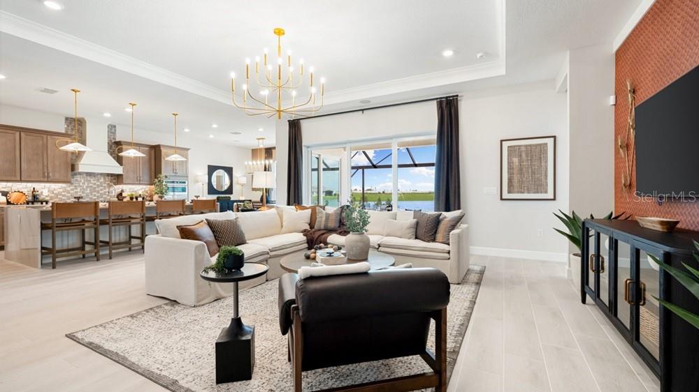 An open-concept living room features a large sectional sofa, a chandelier, and a kitchen island — 13481 MANAROLA WAY, ENGLEWOOD, FL