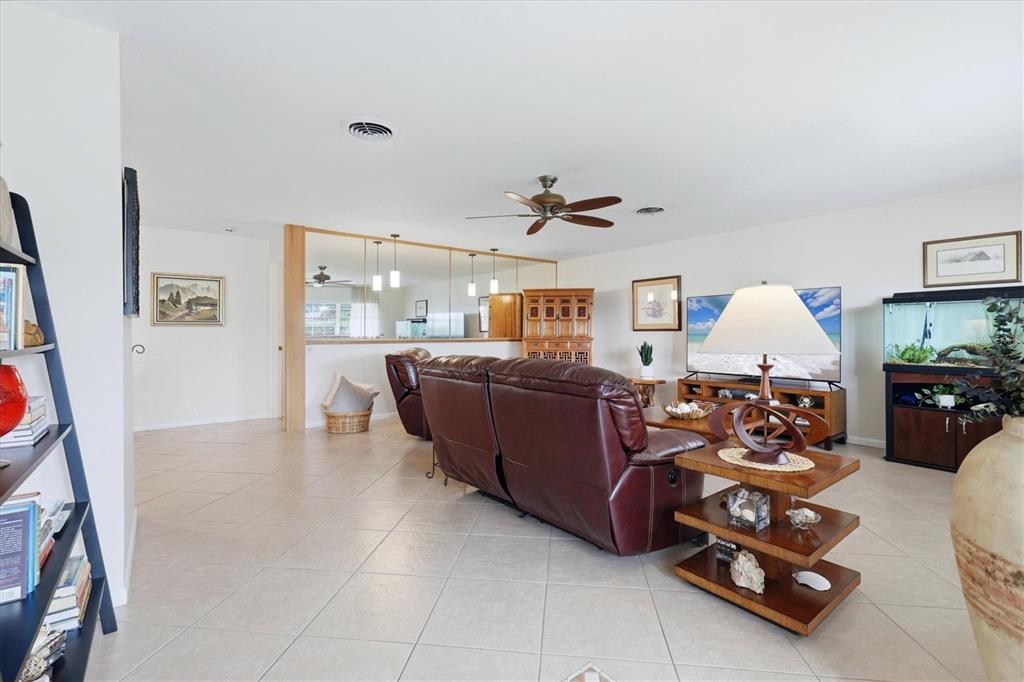 A living room features tile flooring, a leather sofa, a ceiling fan, and mirrored walls — 3612 S LOCKWOOD RIDGE ROAD, SARASOTA, FL