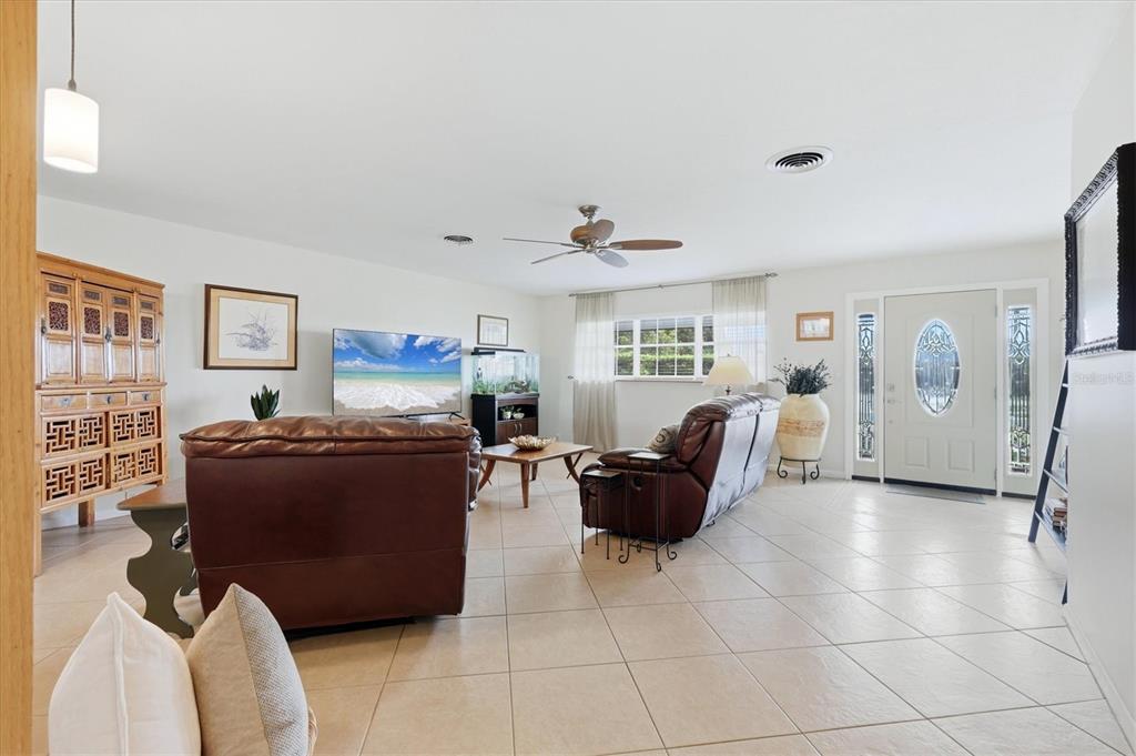 A living room features tile flooring, brown leather furniture, a ceiling fan, and a front door — 3612 S LOCKWOOD RIDGE ROAD, SARASOTA, FL