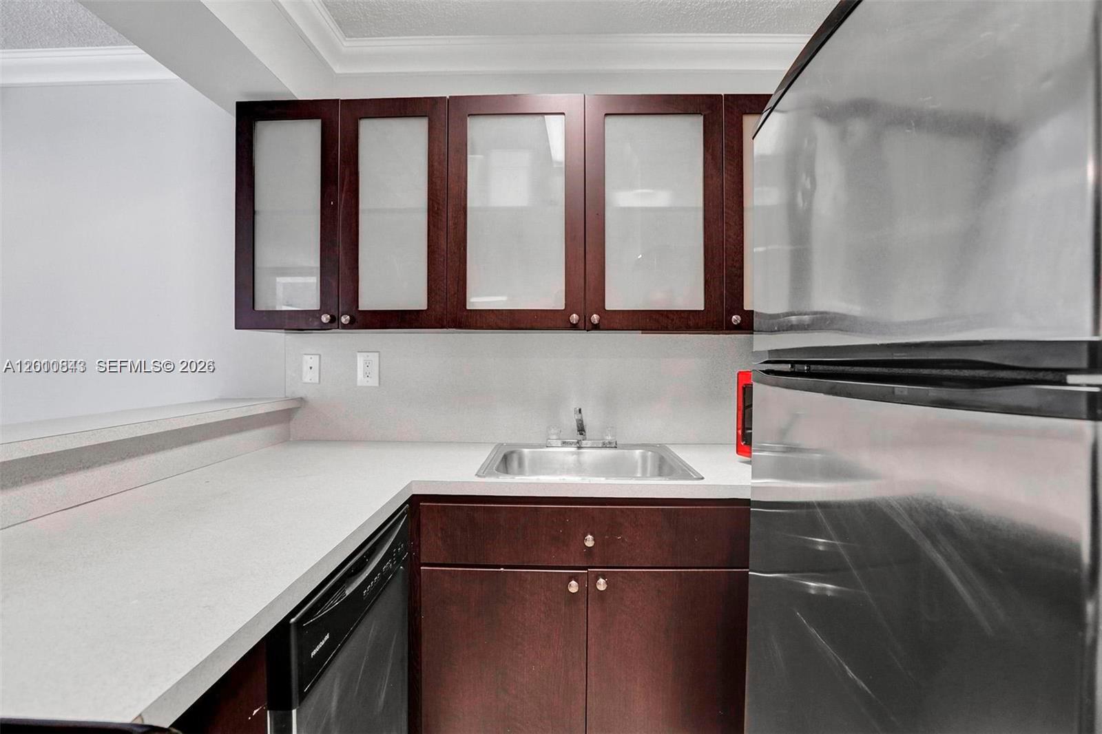 A kitchen features dark wood cabinets with glass inserts, a stainless steel sink, and appliances — 126 SW 17th Rd # 601, Miami FL 33129, MIAMI, FL