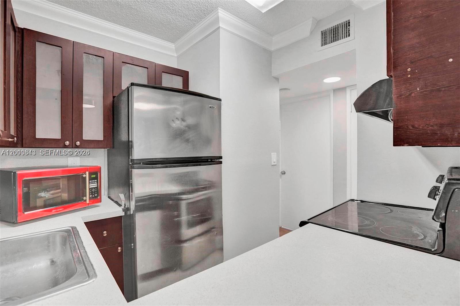 A kitchen features dark wood cabinets, stainless steel appliances, and a red microwave — 126 SW 17th Rd # 601, Miami FL 33129, MIAMI, FL