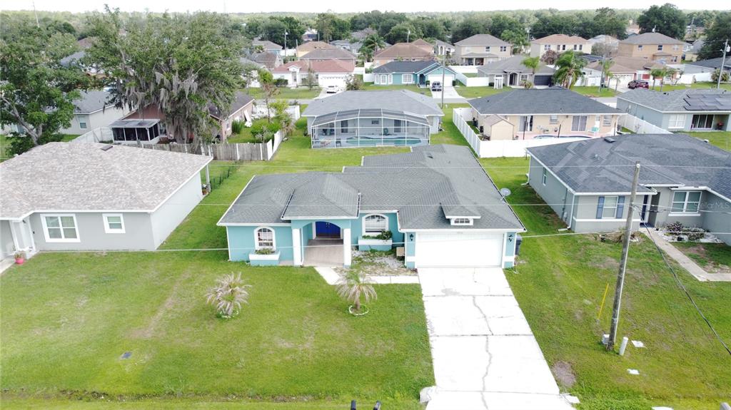 An aerial view shows a teal single-story house with a two-car garage and lawn — 413 FLAMINGO CT, POINCIANA, FL