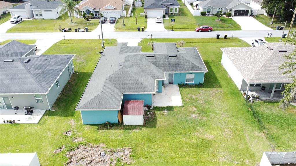 An aerial view shows the backyard and roof of a teal single-family house — 413 FLAMINGO CT, POINCIANA, FL