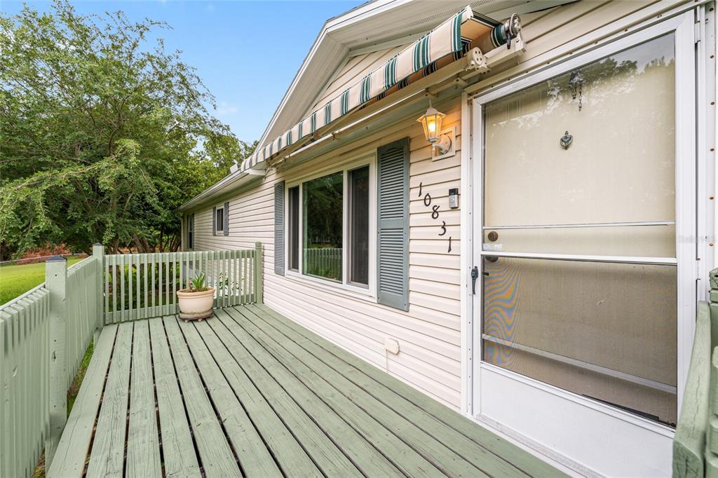 A light-colored house exterior features a green wooden deck, a window with shutters, and an awning — 10831 NW 10TH PLACE, OCALA, FL
