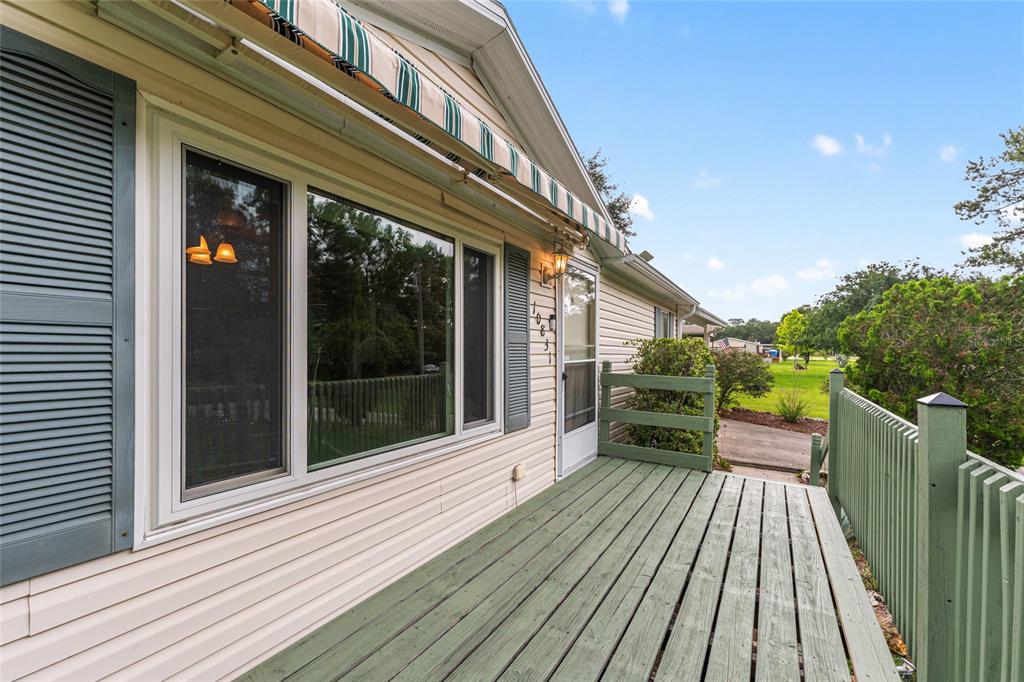 A wooden deck with green railings sits outside a house with beige siding and shutters — 10831 NW 10TH PLACE, OCALA, FL