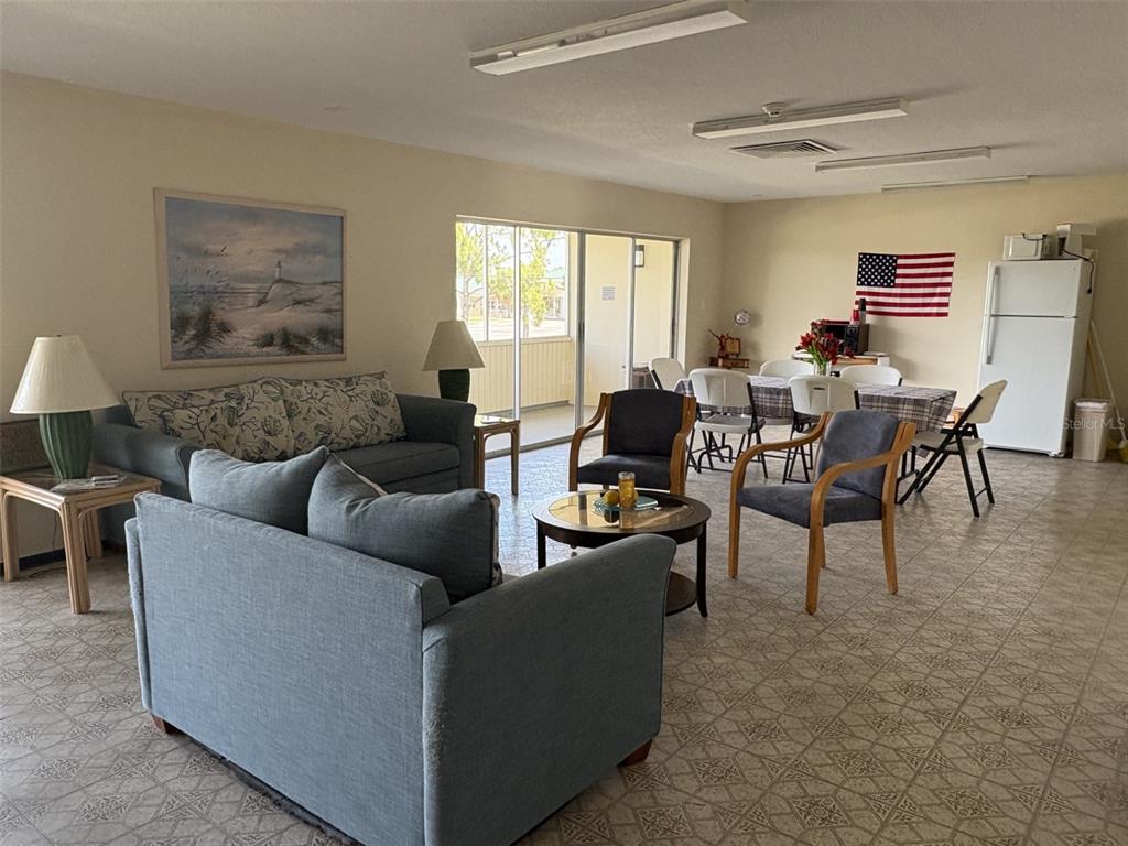 A living and dining area features tiled floors, blue sofas, and a sliding glass door — 21267 GERTRUDE AVENUE UNIT 112, PORT CHARLOTTE, FL