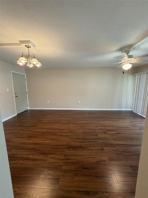 An empty room features wood-look flooring, a chandelier, a ceiling fan, and a sliding door — 21267 GERTRUDE AVENUE UNIT 112, PORT CHARLOTTE, FL