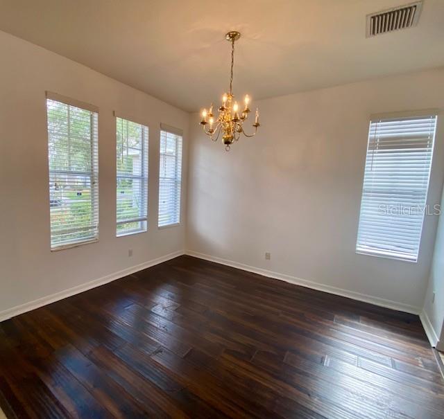 An empty dining room features dark wood flooring, a brass chandelier, and four large windows — 419 HALIFAX BAY COURT, APOLLO BEACH, FL
