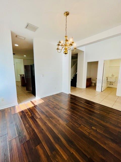 A dining area with dark wood flooring, a gold chandelier, and an adjacent kitchen — 419 HALIFAX BAY COURT, APOLLO BEACH, FL