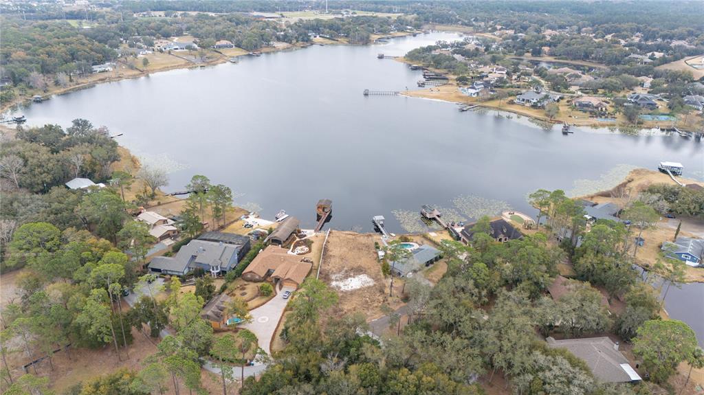 An aerial view shows a lakefront property with a vacant lot between two houses — 601 TUSCANY COURT, SANFORD, FL