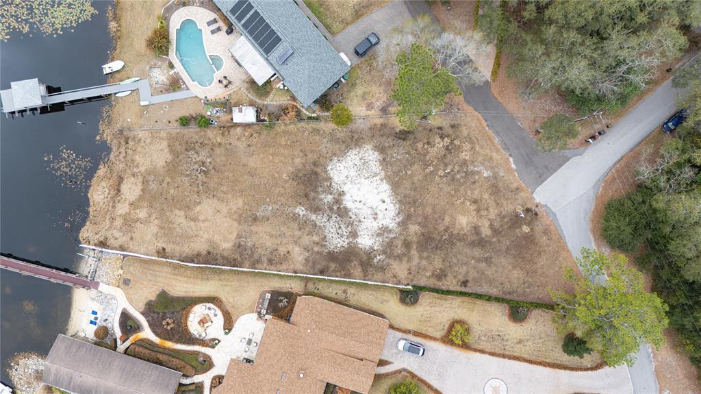 An aerial view shows a vacant, grassy waterfront lot situated between two residential properties — 601 TUSCANY COURT, SANFORD, FL