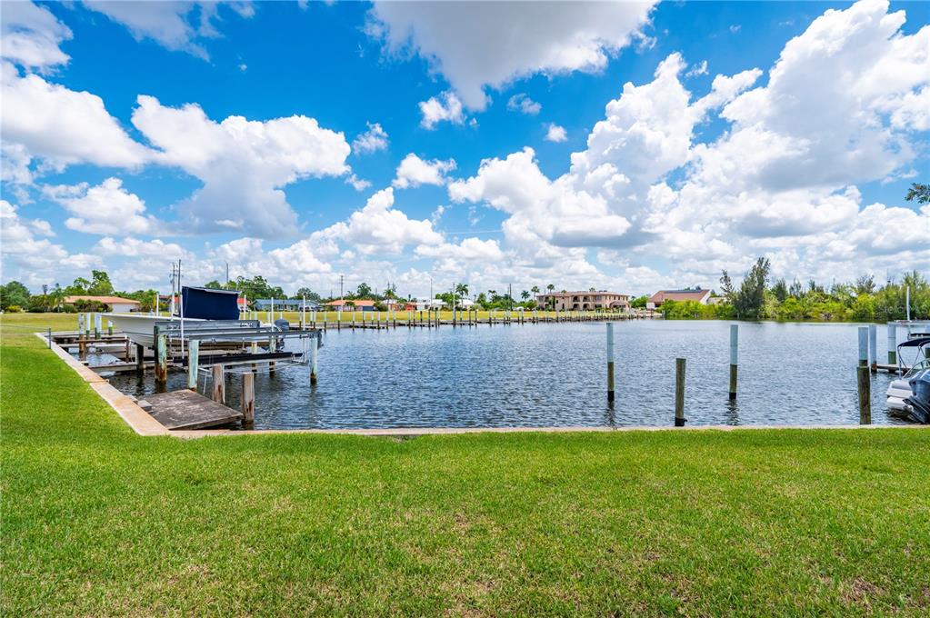 A grassy lawn overlooks a canal with a boat lift and several wooden pilings — 3230 WHITE IBIS COURT UNIT A1-2, PUNTA GORDA, FL
