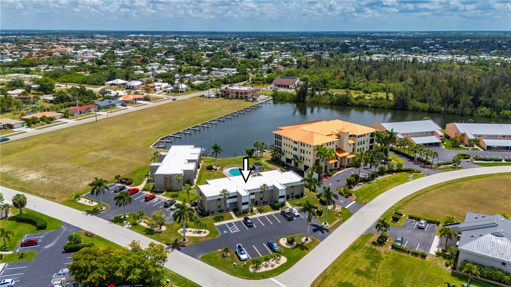 An aerial view shows a multi-story apartment building with a pool and parking lot — 3230 WHITE IBIS COURT UNIT A1-2, PUNTA GORDA, FL