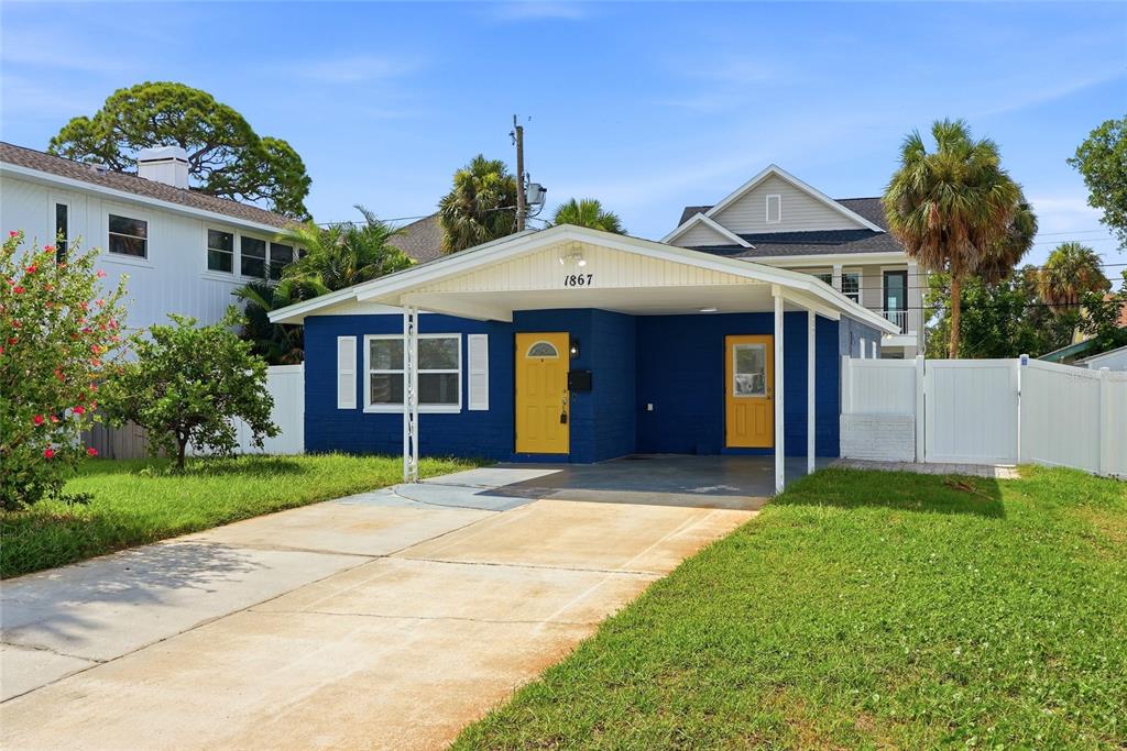 A blue single-story house with a carport, yellow doors, and a concrete driveway — 1867 MICHIGAN AVENUE NE, ST PETERSBURG, FL