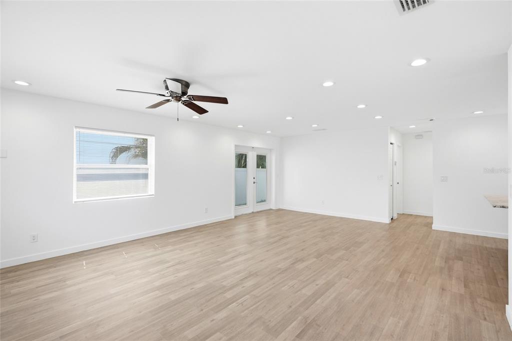 An empty room with white walls, light wood-look flooring, a ceiling fan, and glass doors — 1867 MICHIGAN AVENUE NE, ST PETERSBURG, FL