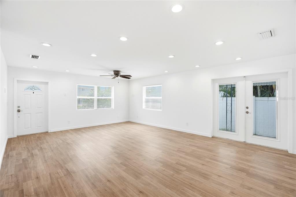 A bright, empty room features white walls, recessed lighting, a ceiling fan, and wood-look flooring — 1867 MICHIGAN AVENUE NE, ST PETERSBURG, FL