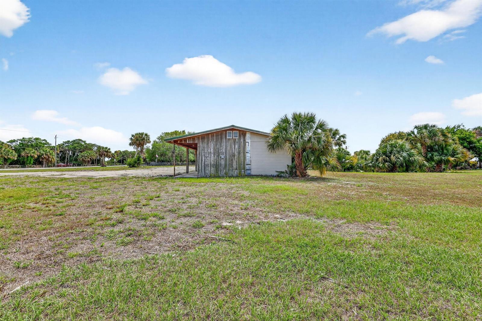 A weathered wooden shed stands in a grassy field under a bright blue sky — Unassigned Address Unassigned, FL, FL
