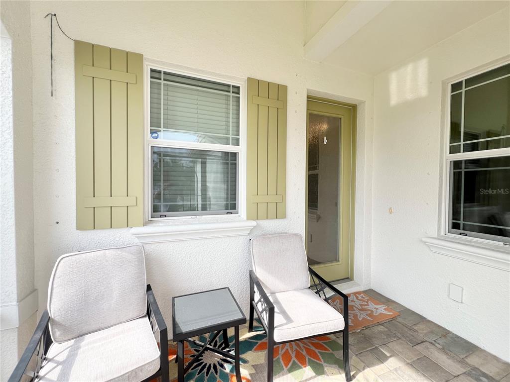 A covered patio features two chairs, a small table, a rug, and a glass-paneled door — 2946 TRUSTEE AVENUE, SARASOTA, FL