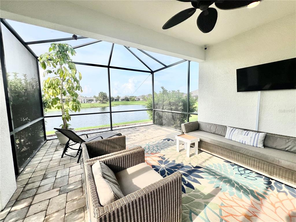 A screened-in patio features outdoor furniture, a ceiling fan, and a view of a lake — 2946 TRUSTEE AVENUE, SARASOTA, FL