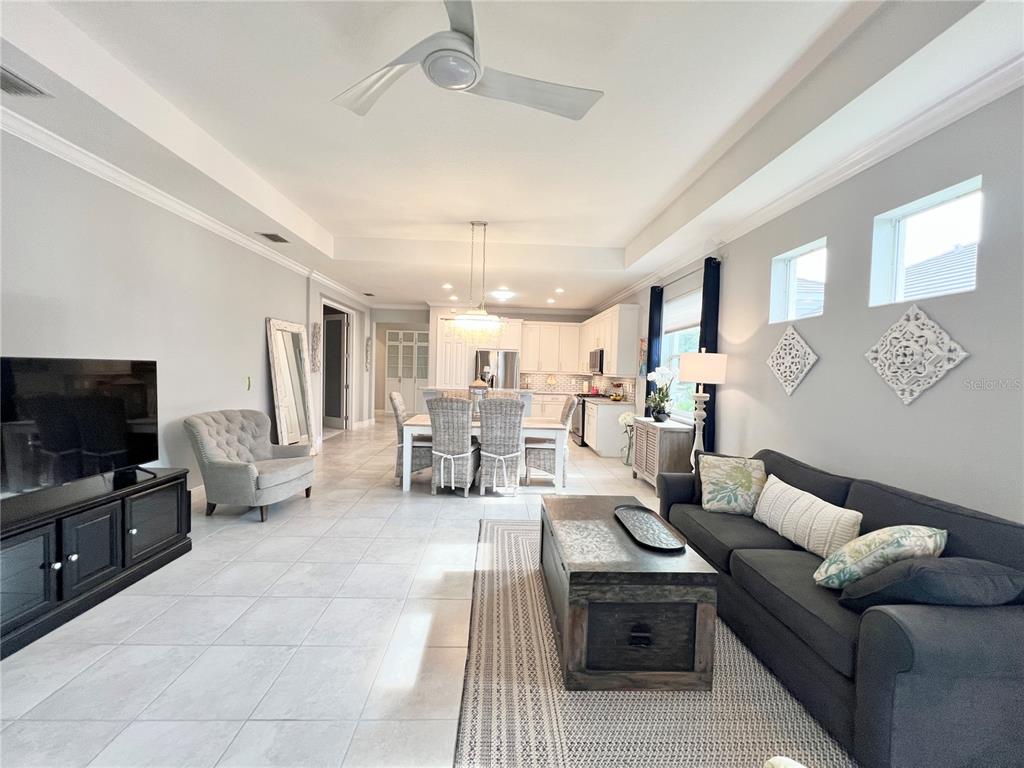 An open-concept living and dining area features tile flooring, a tray ceiling, and white cabinetry — 2946 TRUSTEE AVENUE, SARASOTA, FL