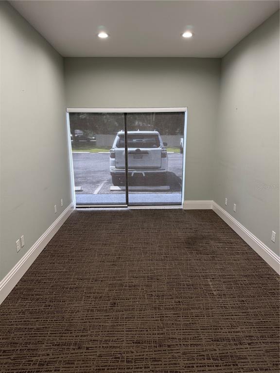 An empty office room with light green walls, brown patterned carpet, and a sliding glass door — 5182 N OCEAN SHORE BOULEVARD UNIT A-2, PALM COAST, FL