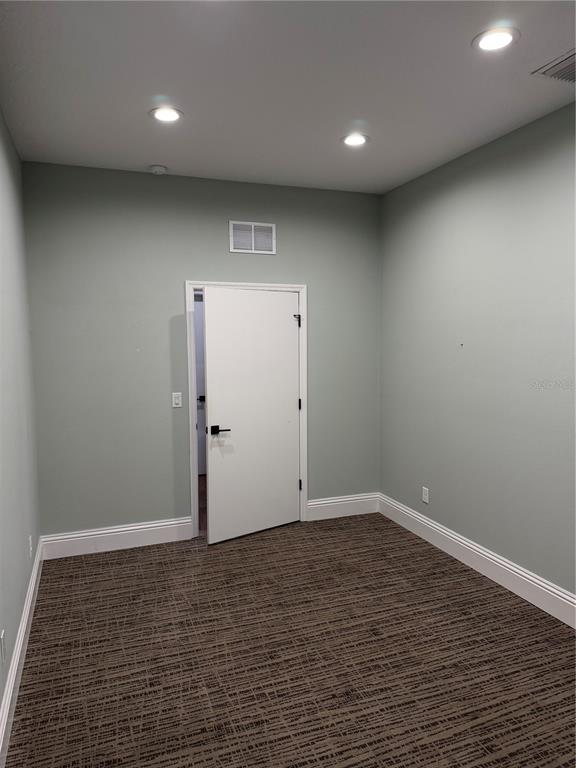 An empty room with light green walls, patterned carpet, and a white door — 5182 N OCEAN SHORE BOULEVARD UNIT A-2, PALM COAST, FL