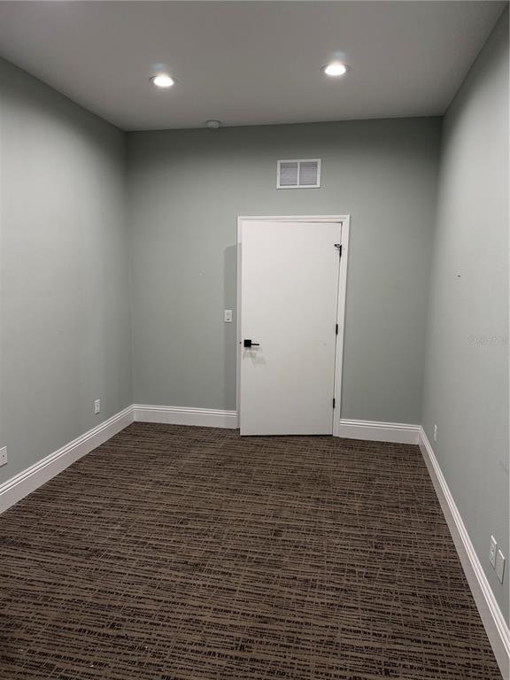An empty room with light green walls, brown patterned carpet, and a white door — 5182 N OCEAN SHORE BOULEVARD UNIT A-2, PALM COAST, FL