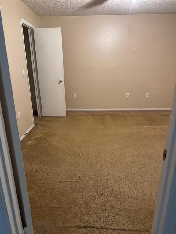 An empty bedroom features beige walls, tan carpeting, and a white door leading to a closet — 956 SALT POND PLACE UNIT 304, ALTAMONTE SPRINGS, FL