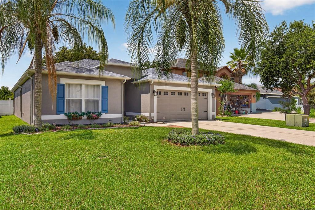 A living room features a grey sofa, a leather ottoman, and a large wall clock — 31806 LOCH ALINE DRIVE, WESLEY CHAPEL, FL