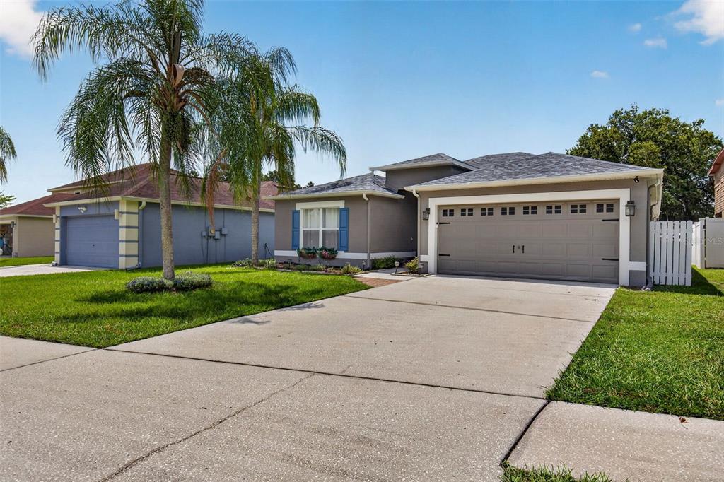 A kitchen features dark blue cabinets, stainless steel appliances, white countertops, and light wood flooring — 31806 LOCH ALINE DRIVE, WESLEY CHAPEL, FL