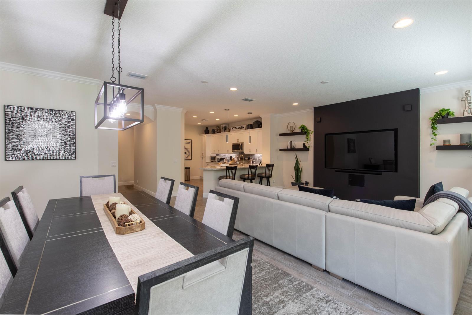 An open-concept living and dining area features a dark dining table, sectional sofa, and kitchen — 168 Crape Myrtle Lane, Wellington FL 33414, WELLINGTON, FL