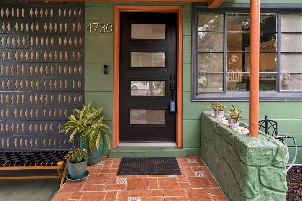 A front porch with a green floor, a black door, and a decorative screen wall — 4730 15TH AVENUE N, ST PETERSBURG, FL