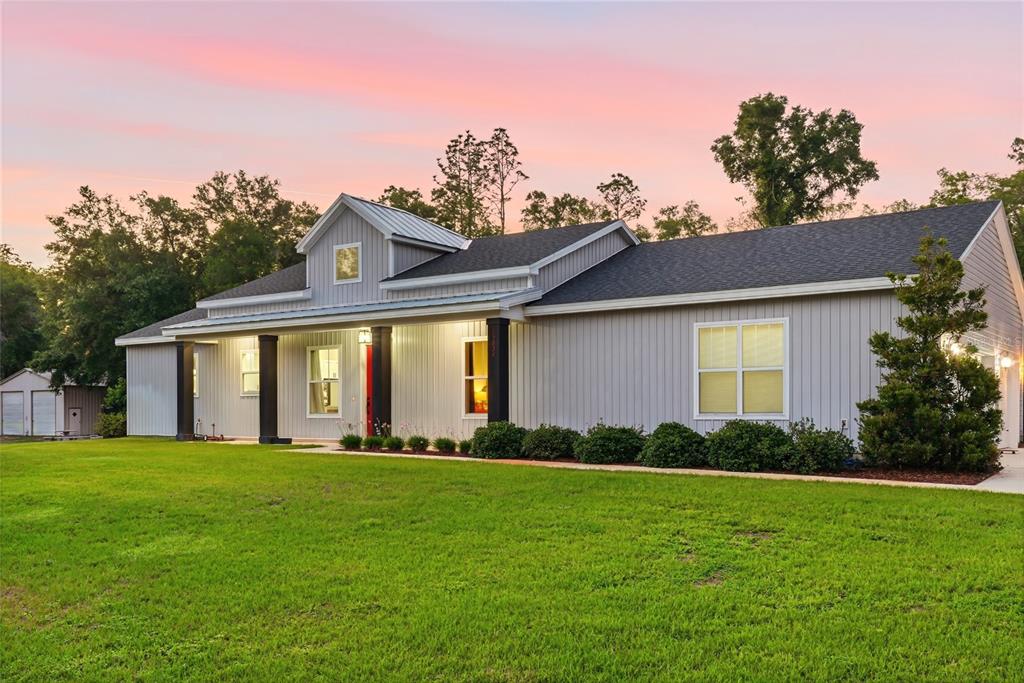 A gray, single-story house with vertical siding and a metal roof at sunset — 13825 SW 51ST LANE, OCALA, FL