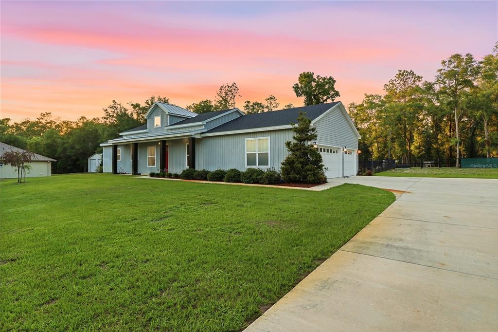 A light gray single-story house with a metal roof and attached garage sits on grass — 13825 SW 51ST LANE, OCALA, FL