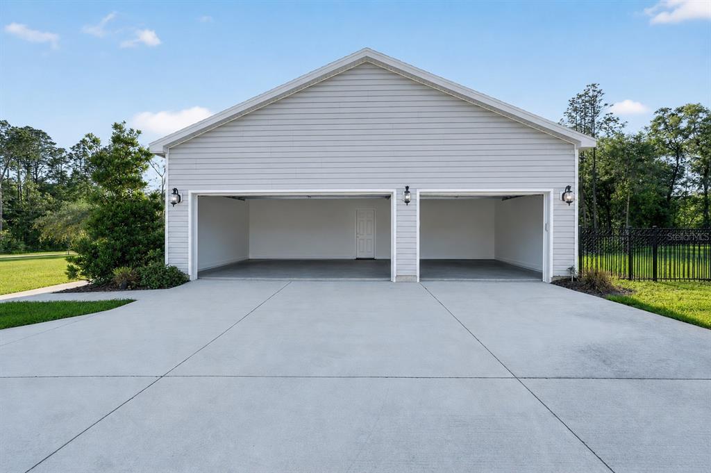 A detached two-car garage with light gray siding and a concrete driveway — 13825 SW 51ST LANE, OCALA, FL