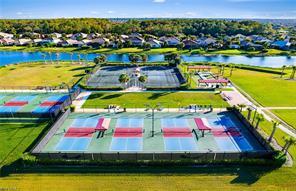 An aerial view shows multiple pickleball and tennis courts located near a lake and houses — 3957 Cranesbill Court, FL 33920, FL