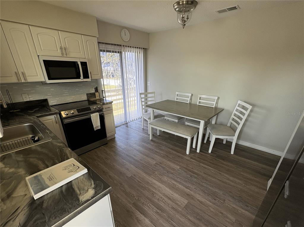 A kitchen with white cabinets and a dining area featuring a table and chairs — 6693 ENGRAM ROAD, NEW SMYRNA BEACH, FL