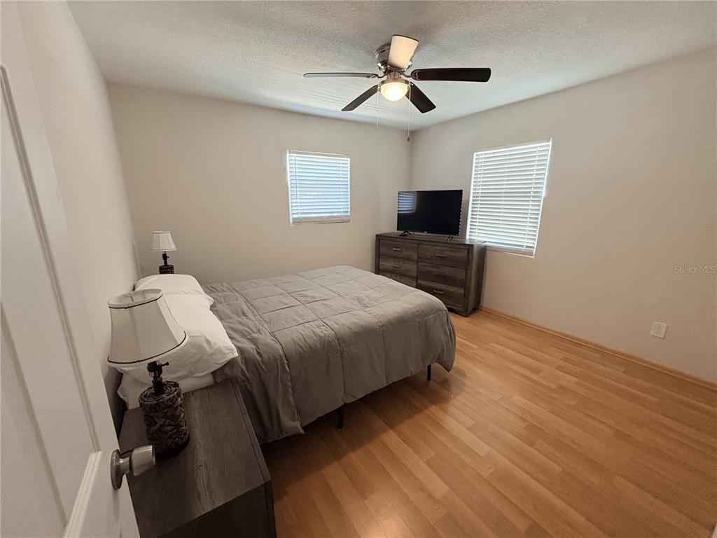 A bedroom features a bed, a dresser with a television, and light wood flooring — 6693 ENGRAM ROAD, NEW SMYRNA BEACH, FL