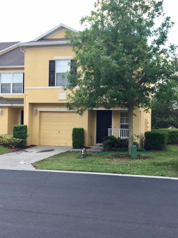 A two-story yellow stucco townhouse features a single-car garage and a front entrance — 3399 CARUSO PLACE, OVIEDO, FL