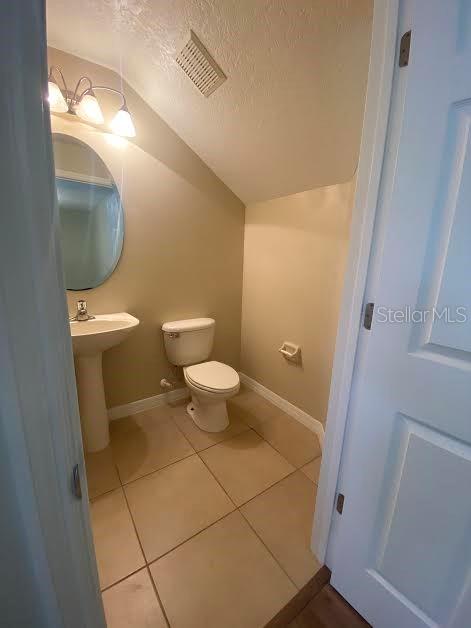 A small half bathroom features a pedestal sink, a toilet, and light-colored tile flooring — 3399 CARUSO PLACE, OVIEDO, FL