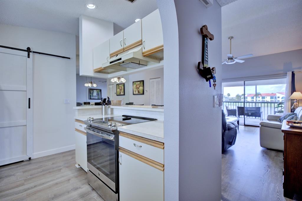 A kitchen with white cabinets and stainless steel appliances opens into a bright living area — 5369 CASABLANCA CIRCLE UNIT K24, SEBRING, FL