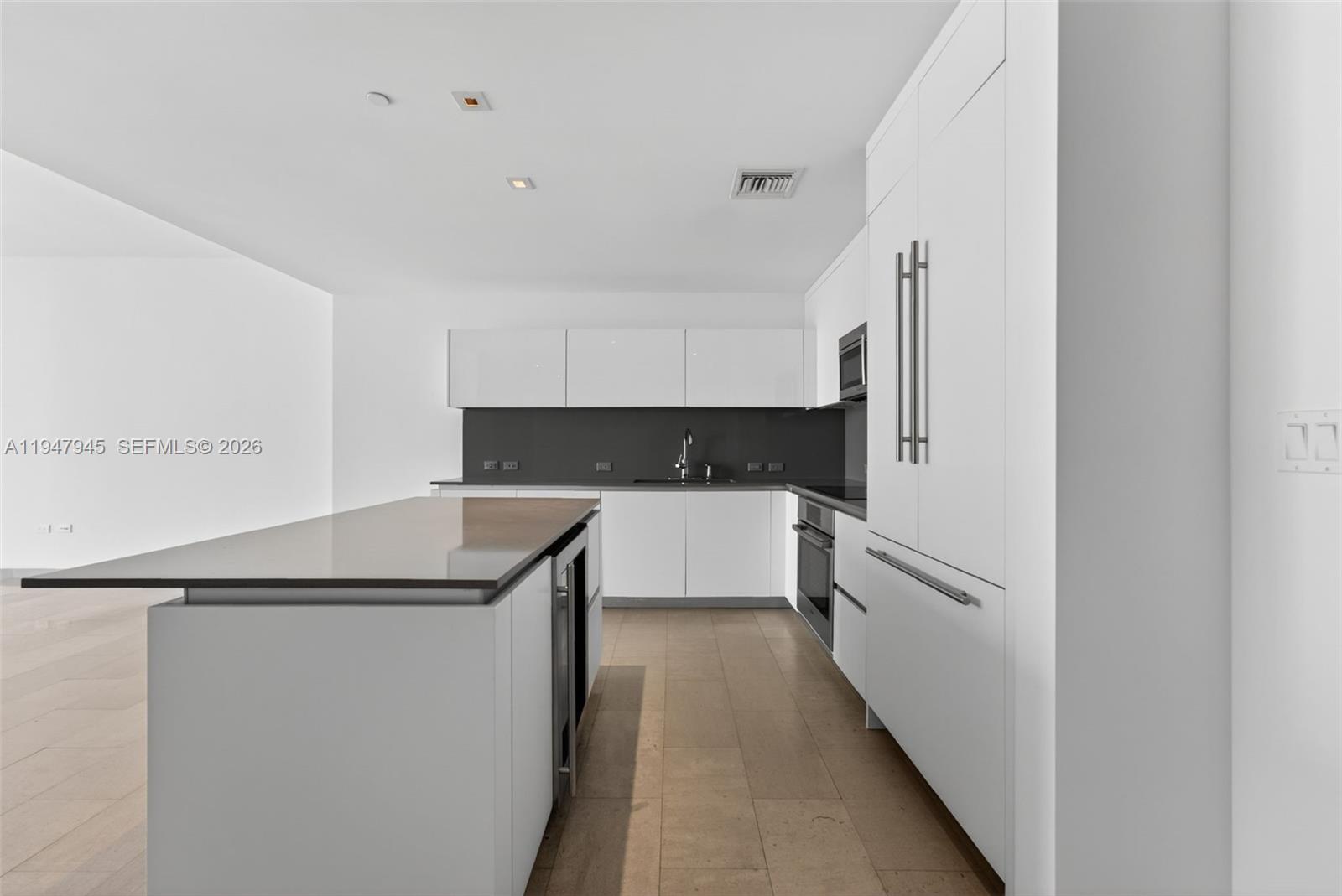 A modern kitchen features white cabinetry, a dark countertop, and a central island — 68 SE 6th St # 2110, Miami FL 33131, MIAMI, FL
