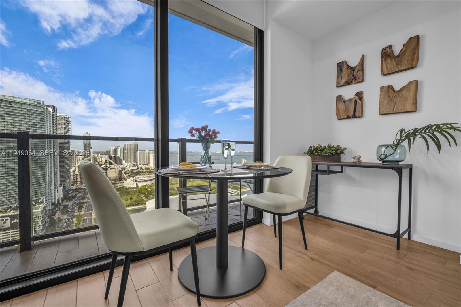 A dining area with a round table, two chairs, and floor-to-ceiling windows overlooking a city — 398 NE 5th St # 3207, Miami FL 33132, MIAMI, FL